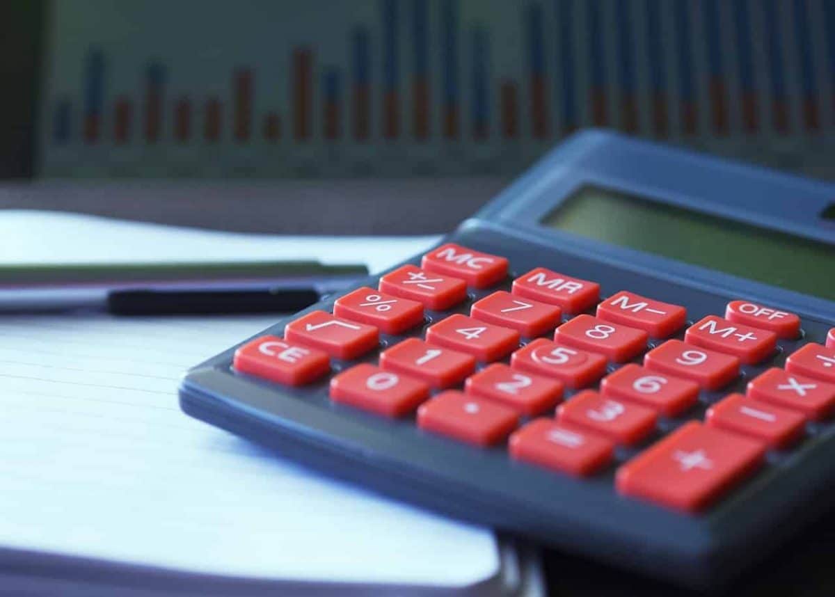 Closeup of a calculator with red buttons atop a notebook