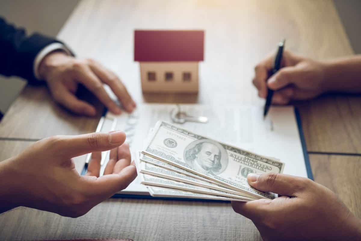 One person handing another cash to pay for a mortgage