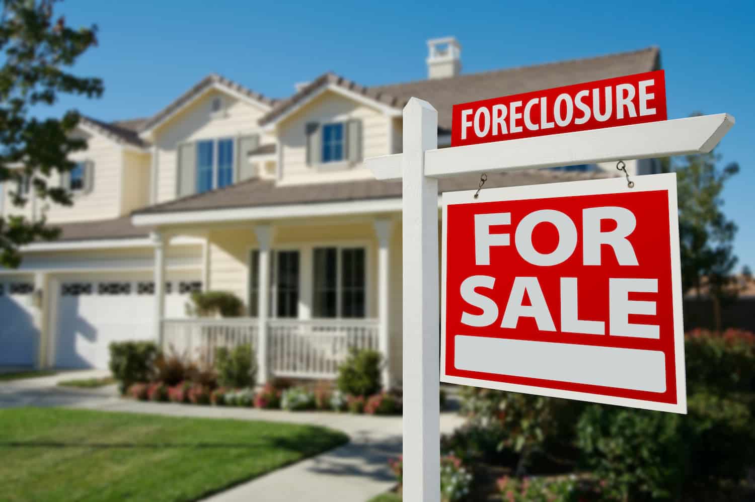 Two-story white house with a foreclosure sign in front of it.