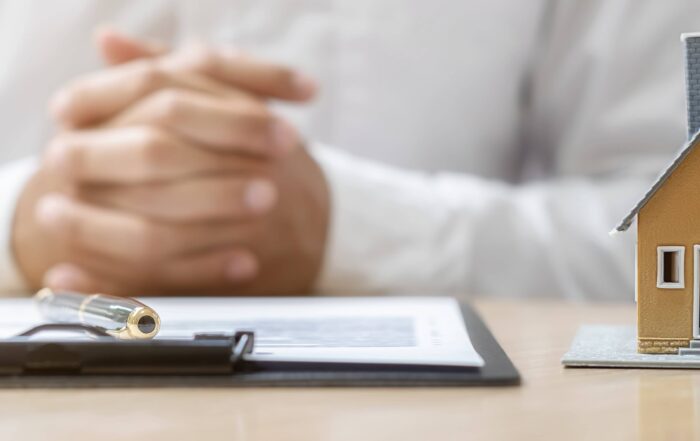 close up of mortgage broker hands paperwork and house to explain hard money vs soft money loans